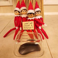 three elfs sitting in front of a computer mouse with a sign that says, look we caught a mouse