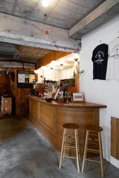 a bar with two stools next to it in a room that has concrete floors