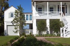 a large white house with two stories and a porch on the second story is surrounded by greenery