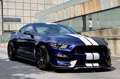 a blue mustang with white stripes parked on the street