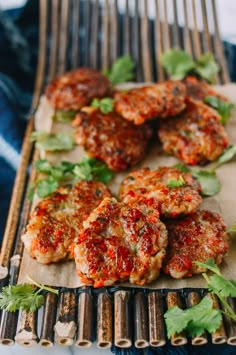 some meat patties are on a tray with parsley and cilantro leaves