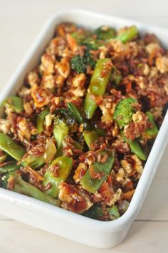 a white dish filled with broccoli and other vegetables