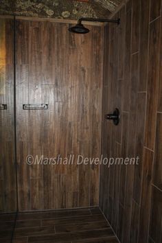 a walk in shower sitting next to a wooden wall