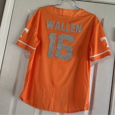 an orange shirt hanging on a door with the name walter 16 written in silver sequins