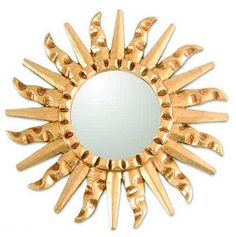 a gold sunburst shaped mirror with spikes on it's sides and a white background