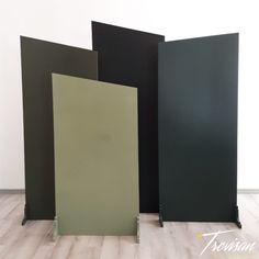 three black and green panels sitting on top of a hard wood floor next to each other