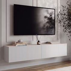 a large flat screen tv mounted to the side of a white cabinet in a living room