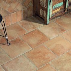 a chair sitting on top of a tiled floor next to a wooden cabinet and door