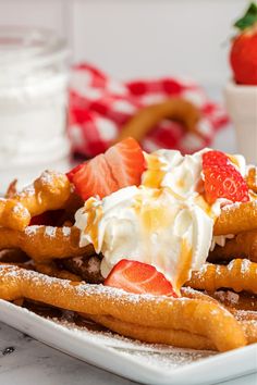 a white plate topped with waffles covered in whipped cream and strawberries