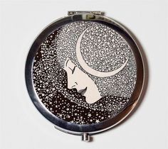 a compact mirror with an image of a woman's face and crescent moon on it