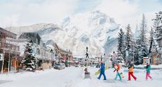 several people walking down a snowy street in front of snow covered mountains and buildings with skis on them