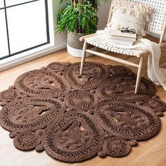 a brown rug is on the floor in front of a chair and potted plant