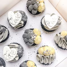 nine decorated cupcakes in the shape of hearts and flowers on a white box