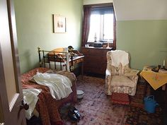 a bedroom with two beds, a chair and a desk in the corner next to a window