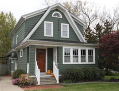 a green house with white trim on the front door and steps leading up to it