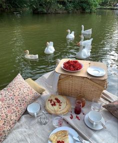 a picnic table with food on it and swans in the water