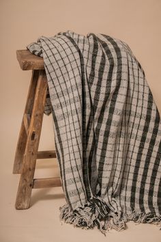 a black and white checkered blanket sitting on top of a wooden stool next to a ladder