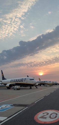 three airplanes parked on the tarmac at an airport with sunset in the back ground