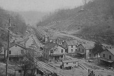 an old black and white photo of houses on the side of a hill with trees