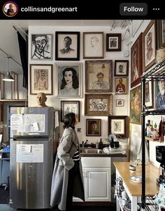 a woman standing in front of a refrigerator freezer next to a wall full of pictures