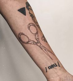 a person with a tattoo on their arm holding scissors