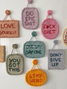 six crocheted purses hanging from hooks with words written on them and saying, don't give up