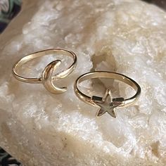 two rings sitting on top of a rock with a star and moon in the middle