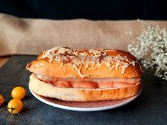 a sandwich with meat and cheese on a plate next to some oranges in the background