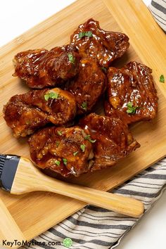 a wooden cutting board topped with meat covered in sauce