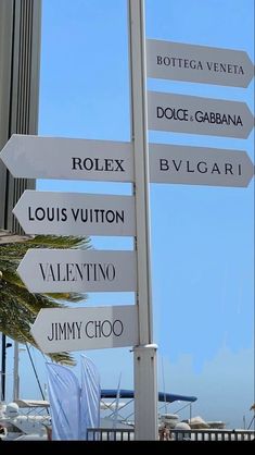 a pole with many signs on it in front of a building and palm tree outside