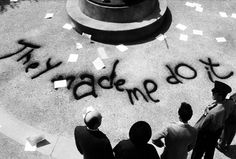 black and white photograph of people standing in front of a monument with writing on it