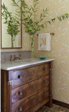 a bathroom with a wooden dresser, mirror and plant on it's countertop