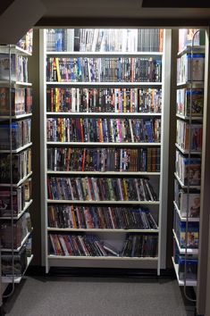 there is a large amount of dvds on the shelves in this room and it looks like they are full of them