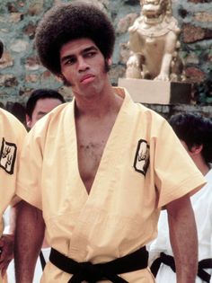 two men in yellow kimonos standing next to each other and one man with an afro