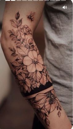 a woman's arm with flowers and butterflies tattooed on the arm, in black and white