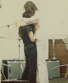 two people standing next to each other with guitars in the background