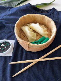 two chopsticks are next to a bowl with dumplings in it on a table