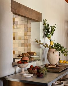 two vases filled with fruit sitting on top of a wooden table next to a mirror