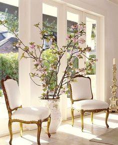 two chairs and a vase with flowers in it