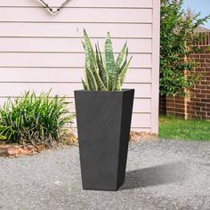 a tall black planter sitting in front of a house