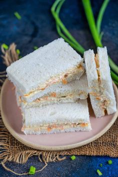 three sandwiches stacked on top of each other on a plate next to some scallions