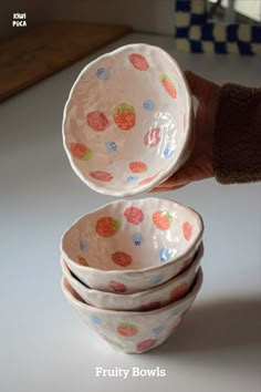 a hand holding a stack of bowls on top of a table