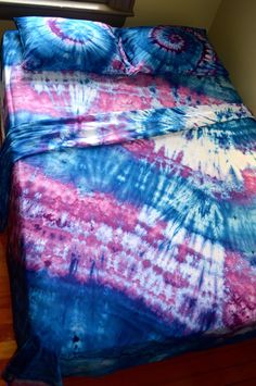 a bed covered in a blue and pink tie dye comforter