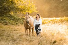 a woman is walking her horse through the field