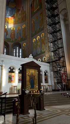 the interior of a church with many paintings on the wall and candles in front of it