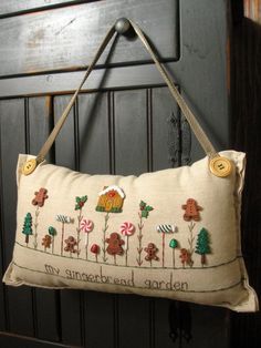 a decorative pillow hanging on a door handle with an embroidered garden scene in the middle