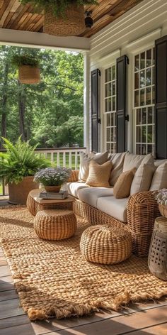 an outdoor living area with wicker furniture and plants on the porch, surrounded by large windows