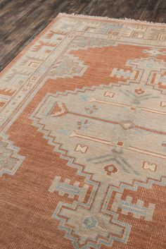 an orange and blue area rug on a wooden floor with wood floors in the background