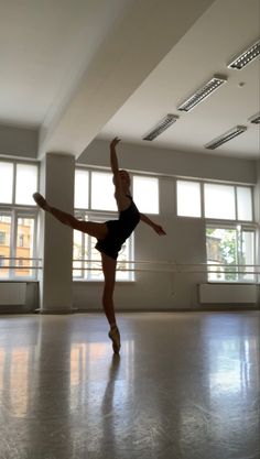 a ballerina is practicing in an empty room with large windows on the wall and floor