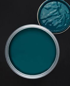 two tins of blue paint sitting on top of a black table next to each other